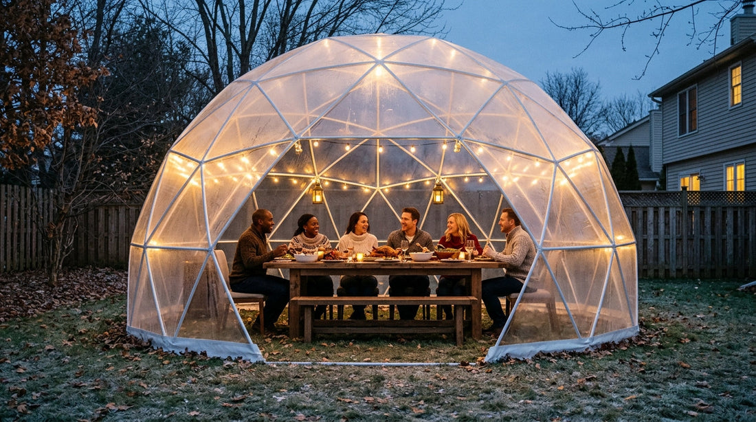 Friends dining inside a clear bubble tent dome in a backyard on a cold evening